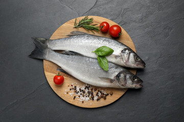 Sea bass fish and ingredients on black table, top view