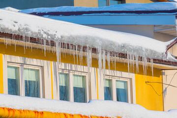 Icicles hanging from the roof of the house on a bright sunny winter day.