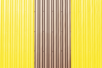 Yellow and brown corrugated sheets. Sheets of metal profile screwed to the wall with self-tapping screws.