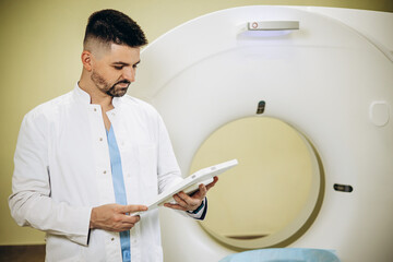 Man doctor with medical report by the MRI scanner