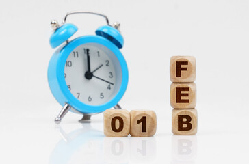 On a white background, a blue alarm clock and a calendar with the inscription - February 1