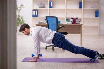 Young male employee doing sport exercises during break