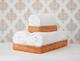 Obraz na płótnie Canvas White soft towels in a wicker basket on a light background in the bathroom