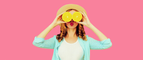 Summer portrait of cheerful young woman covering her eyes with slices of orange fruits and looking for something wearing travel straw hat on pink background - Powered by Adobe