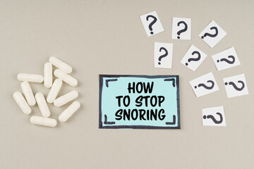 On a gray surface there are question marks and a blue sticker with the inscription - How to stop snoring