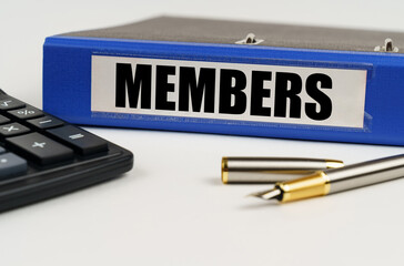 On a white surface, a calculator, a pen and a folder with the inscription - Members