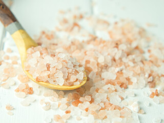 Fototapeta na wymiar Himalayan pink salt in crystals scattered on a wooden table