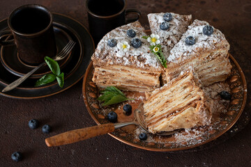 Cake "Napoleon" from puff pastry, decorated with blueberries and flowers.