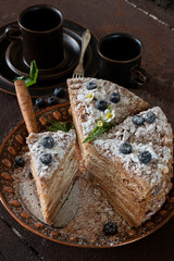 Cake "Napoleon" from puff pastry, decorated with blueberries and flowers.