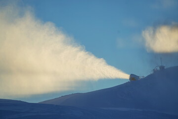 Fototapeta premium Snow cannon in winter mountains. Snow-gun spraying artificial ice crystals. Machine making snow