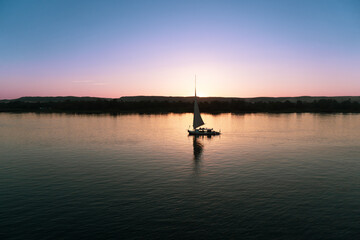 Typical Egyptian boat, sailing on the Nile river at sunset.