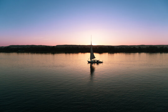 Typical Egyptian boat, sailing on the Nile river at sunset.