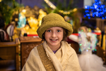  a boy actor dressed as a shepherd stands in front of the nativity scene in the church, waiting for...