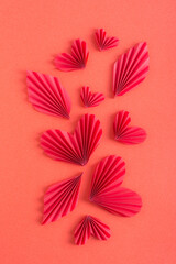 Vertical red background with origami hearts and leaves. Monochrome concept