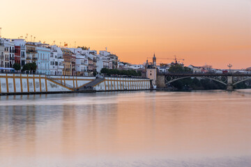 Fototapeta na wymiar Sunset over the authentic neighborhood of Tirana in Seville with views on Calle Betis, Torre Sevilla and with awesome reflections in the river Guadalquivir, creating magic atmosphere and views