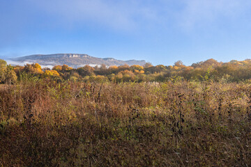 Autumn morning in a mountainous area, a panorama of mountains in a blue haze and the rising sun.