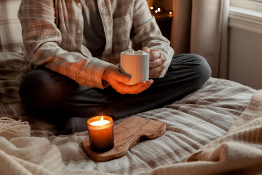 A Caucasian Man Relaxing At Home, Lighting Candle, Drinking Coffee In Bed