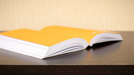 An open book lies diagonally on a dark wooden table