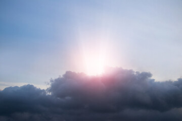 Naklejka na ściany i meble The sun and a bright sunbeam appear from behind a dark cloud
