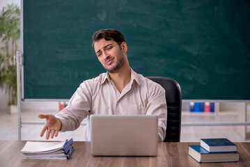 Young male teacher sitting in the classroom