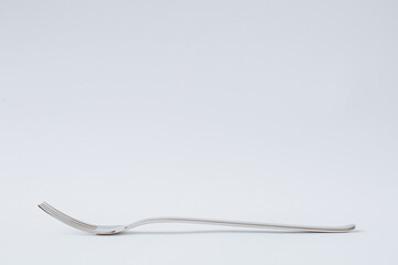 Stainless steel fork for eating on white background, kitchenware, copy space, close-up