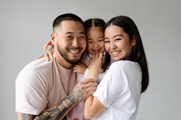 Portrait of cheerful young asian family with daughter looking at camera isolated on grey