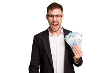 Young business caucasian man holding euro banknotes isolated cut out screaming very angry and aggressive.