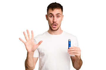Young caucasian man holding a vaporizer cut out isolated smiling cheerful showing number five with fingers.