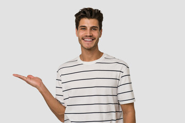 Young handsome caucasian man isolated on white background showing a copy space on a palm and...