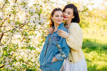 two attractive women hugging in a spring garden. 