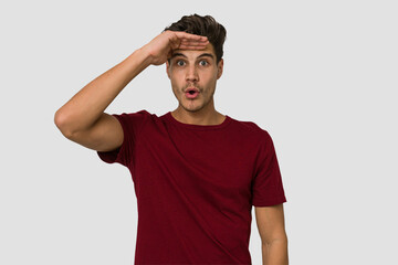 Young handsome caucasian man isolated on white background looking far away keeping hand on forehead.