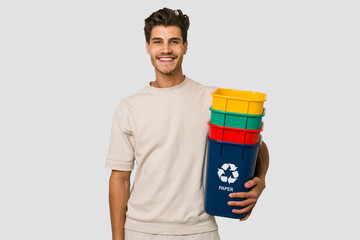 Young caucasian man holding recycling bins isolated on white background