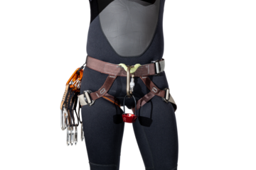 Person wearing rock climbing harness with carabiners, quickdraws, and atc belay device wearing a black wetsuit for outdoor adventures isolated on a white background. 