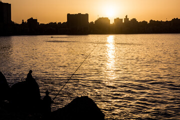 Silhouette of fishermen and a skyline of Alexandria, Egypt