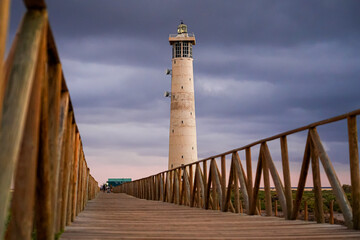 Wooden boardwalk going over marshland towards the Morro Jable lighthouse, built out of concrete in 1991 on the Jandia Peninsula of Fuerteventura in the Canary Islands, Spain
