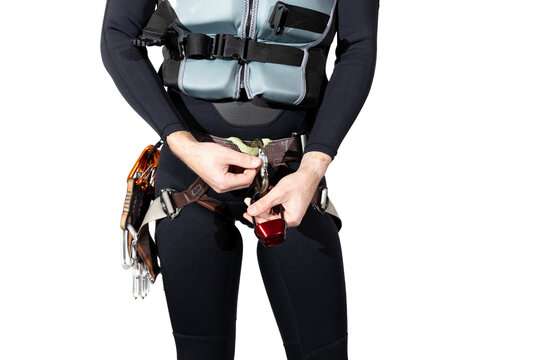 Man wearing a black wetsuit with a life jacket and climbing harness for canyoneering with a rappel device in hand isolated on a white background. Climbing harness with quickdraws and carabiners. 