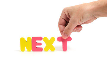 Man hand composes the word next in letters on white background.