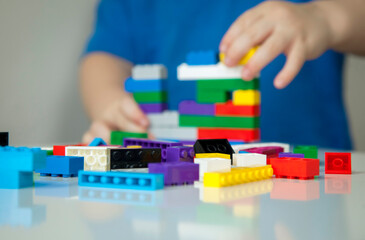 Boy plays colorful multi-colored cubes and cars on the table. Early development and learning. 