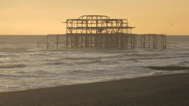 Brighton west pier ruin in evening light, rough seas with breaking waves