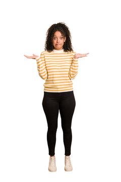 Young african american woman with curly hair cut out isolated confused and doubtful shrugging shoulders to hold a copy space.