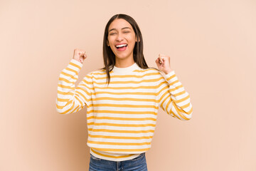 Young colombian woman isolated on beige background cheering carefree and excited. Victory concept.