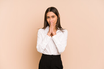 Young colombian woman isolated on beige background covering mouth with hands looking worried.