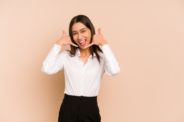 Young colombian woman isolated on beige background showing a mobile phone call gesture with fingers.