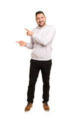 Full body adult latin man cut out isolated pointing with forefingers to a copy space, expressing...