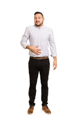 Full body adult latin man cut out isolated touches tummy, smiles gently, eating and satisfaction...