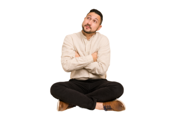 Adult latin man sitting on the floor cut out isolated dreaming of achieving goals and purposes