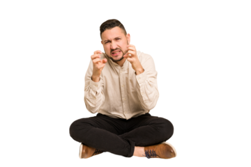 Adult latin man sitting on the floor cut out isolated upset screaming with tense hands.