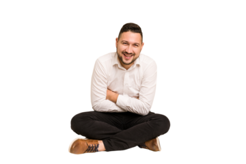 Adult latin man sitting on the floor cut out isolated laughing and having fun.