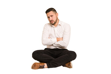 Adult latin man sitting on the floor cut out isolated unhappy looking in camera with sarcastic expression.