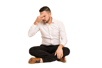Adult latin man sitting on the floor cut out isolated having a head ache, touching front of the face.